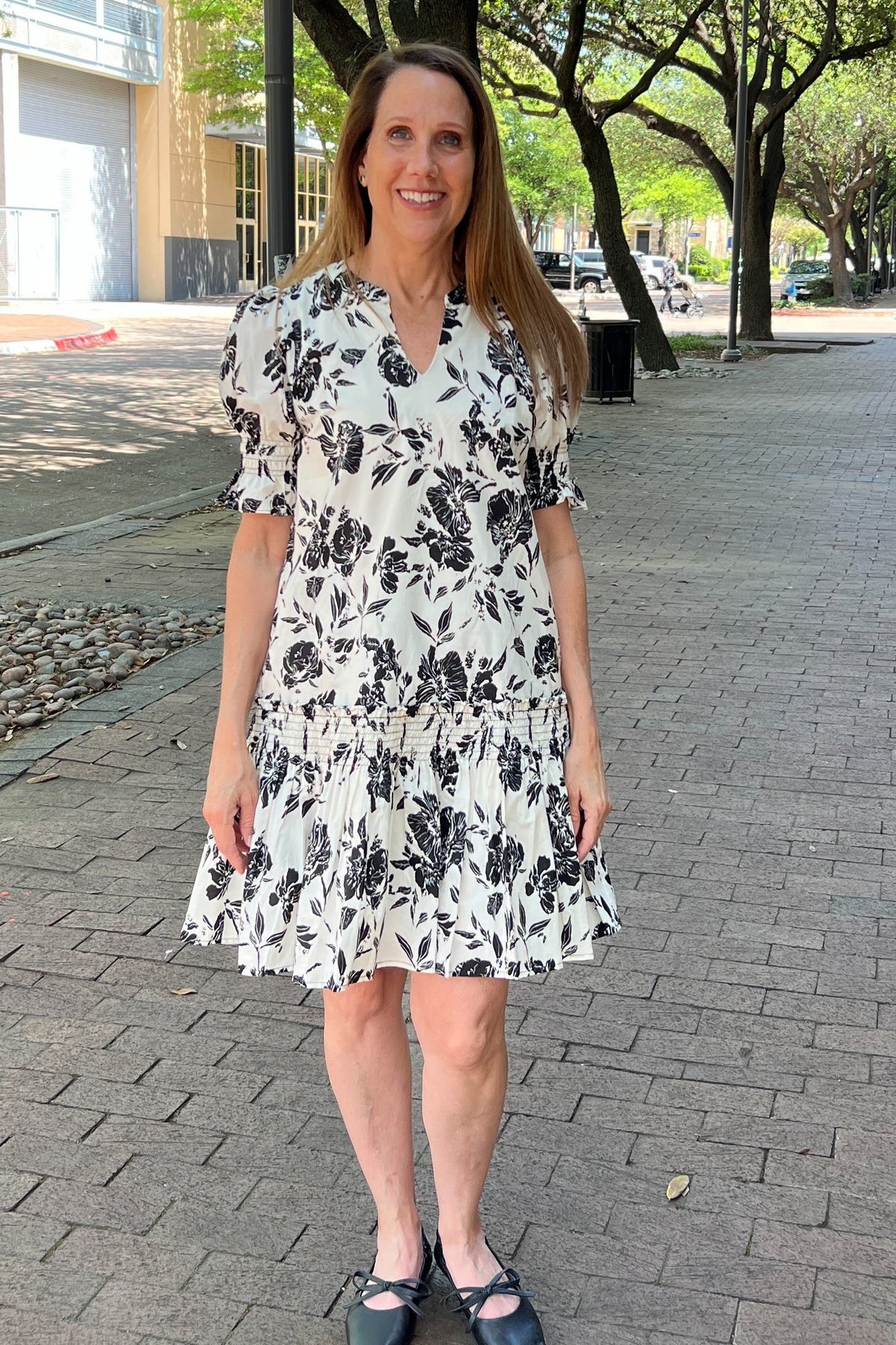 Charming white summer dress with a black floral pattern. Slight puff sleeve with smocked cuff just above the elbow. Drop waist had a ruffle band above the tier hem. Lined and has pockets. 