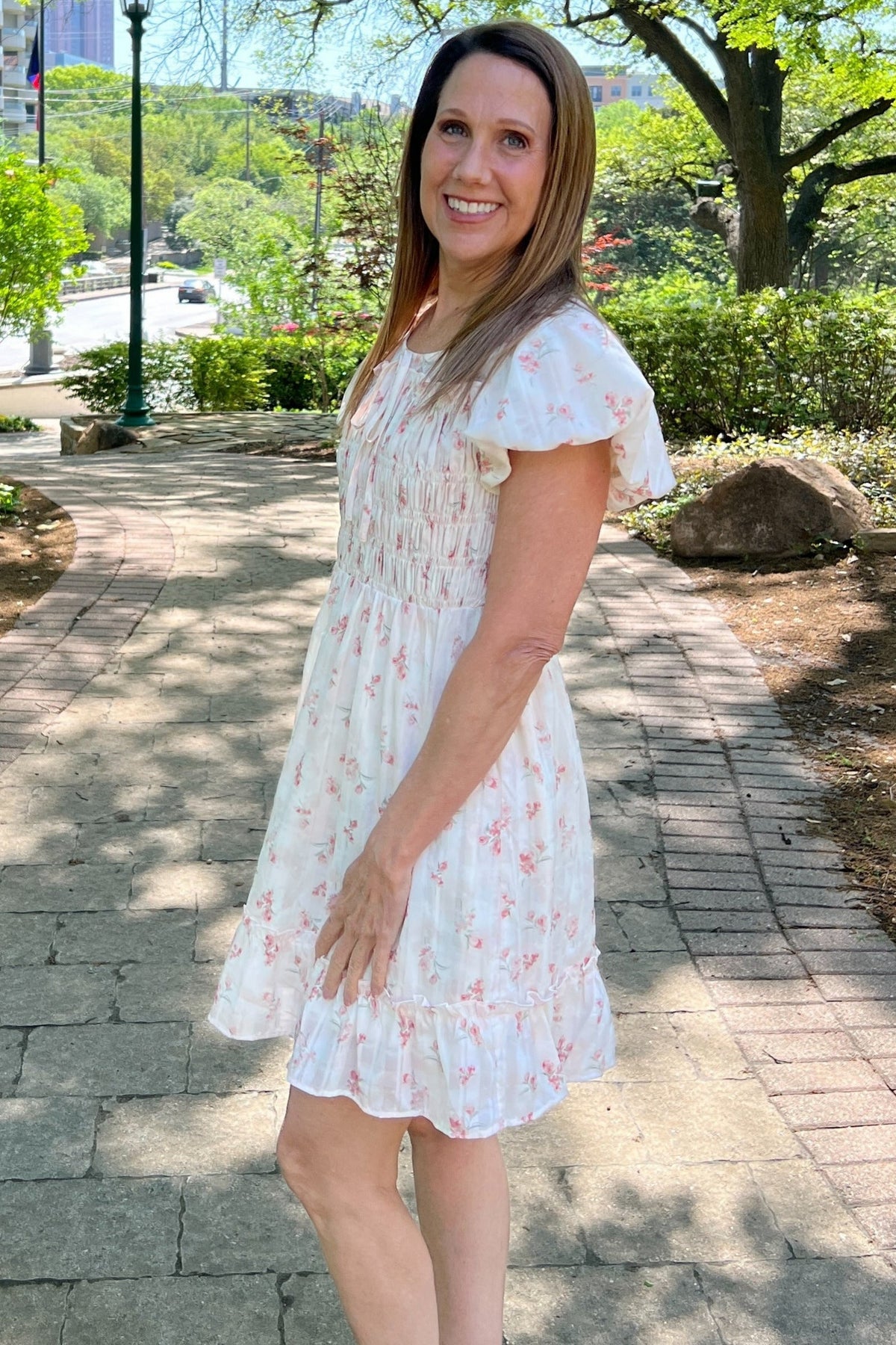 Sweet pink ditsy floral dress is darling for upcoming end-of-year parties and showers. Sleeves are slightly puffed, and the crew-neck collar has a bow detail. The bodice is smocked, and the dress is fully lined. 