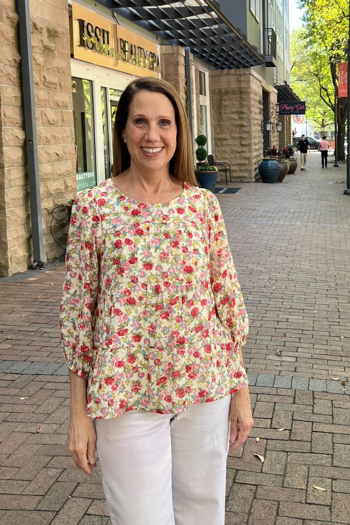 Buttery cream tiered blouse with rose, red and green spring floral pattern. Scoop neck line. Three-quarter length sleeves with elastic cuff. Top is fully lined.