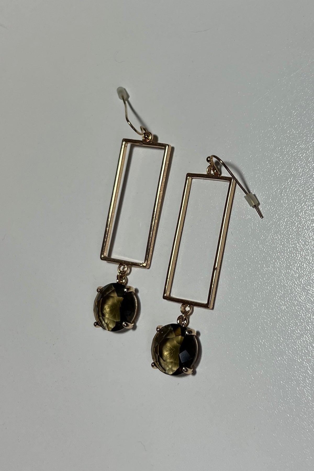 Earrings with a rectangular gold shape with synthetic andalusite stone. Hook earring back. Shown on a white background. 