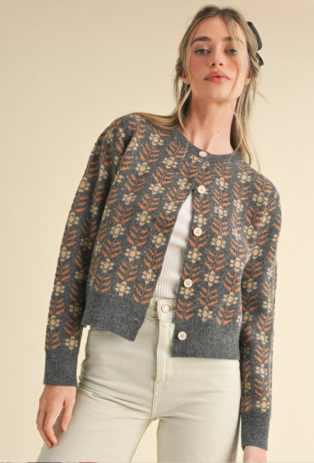 Front view of gray cardigan. It's a great winter staple to layer for warmth. It has a rust/cinnamon and ivory floral pattern on a gray background.