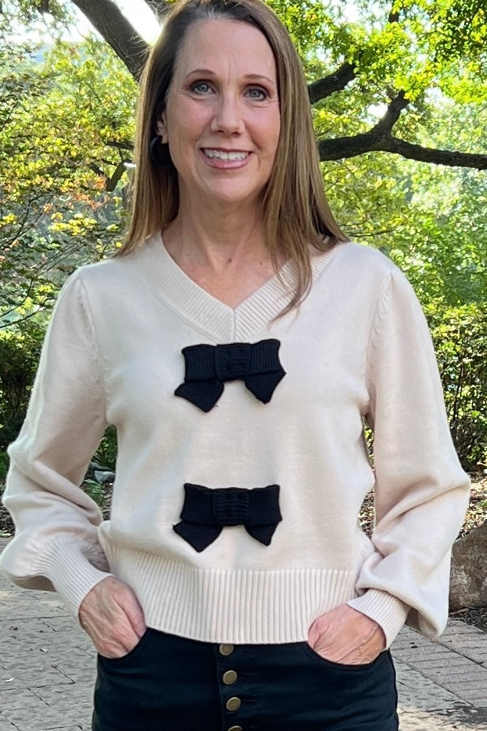 Bring on the bow season! This sweater is so cute on, and it is so soft! The taupe base color is trending, and the black bow details add elegance. The v neck is not too deep, and the cuffed sleeves fit right at the wrist. 