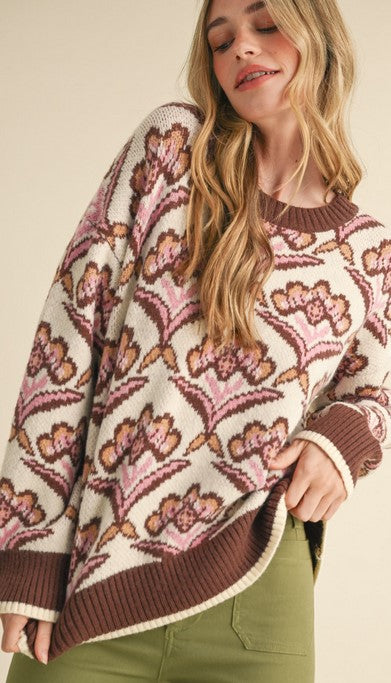 Front view of floral sweater brings together all the fall colors--taupe, chocolate, AND mauve! Its round neckline, cuffs, and hem are chocolate brown for a bold pop of color.